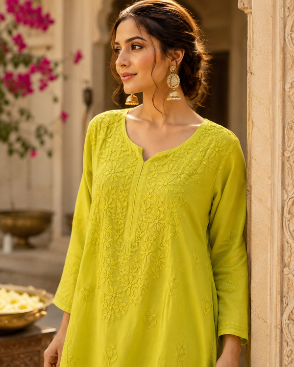 Woman wearing a bright green traditional outfit with floral decorations in the background