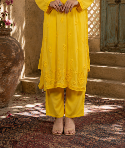 Person wearing a yellow traditional outfit standing in a rustic outdoor setting.