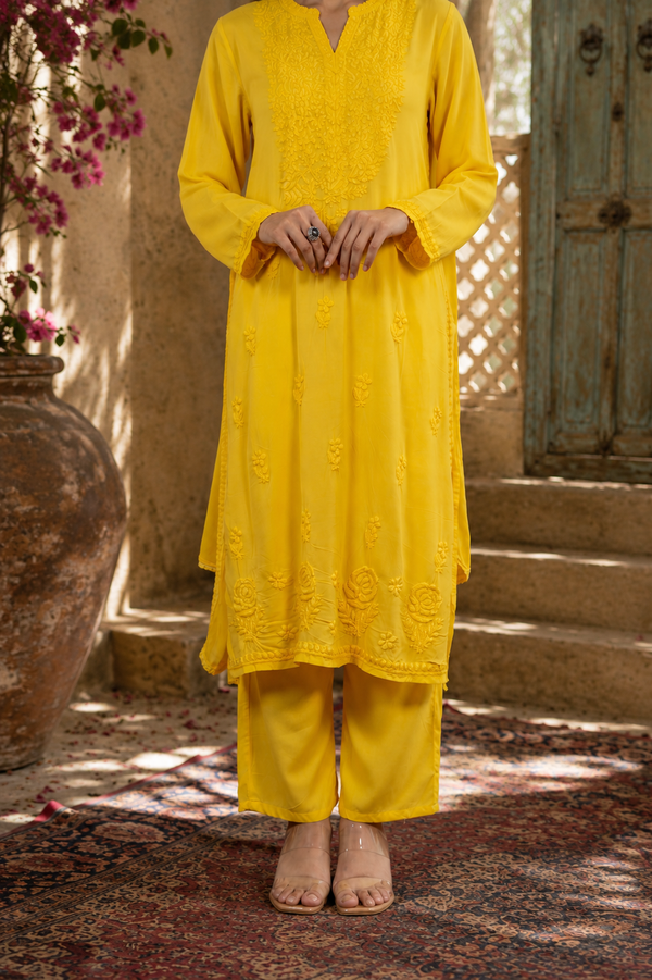 Person wearing a yellow traditional outfit standing in a rustic outdoor setting.