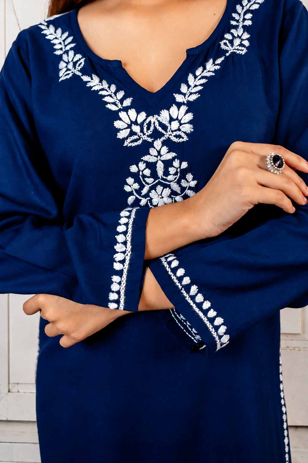 Navy blue dress with white embroidery on a neutral background