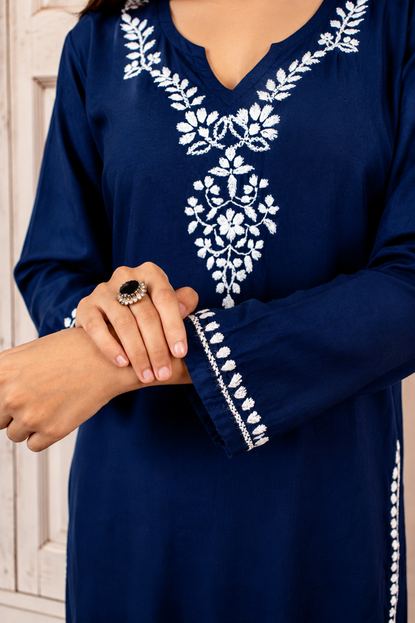 Navy blue dress with white embroidery on a neutral background