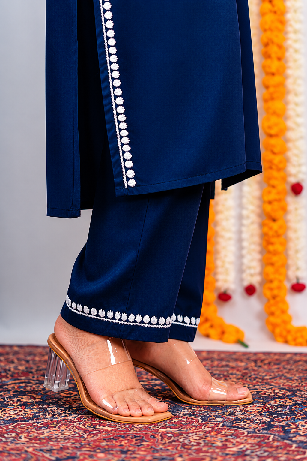Navy blue traditional outfit with transparent heels on a patterned floor.